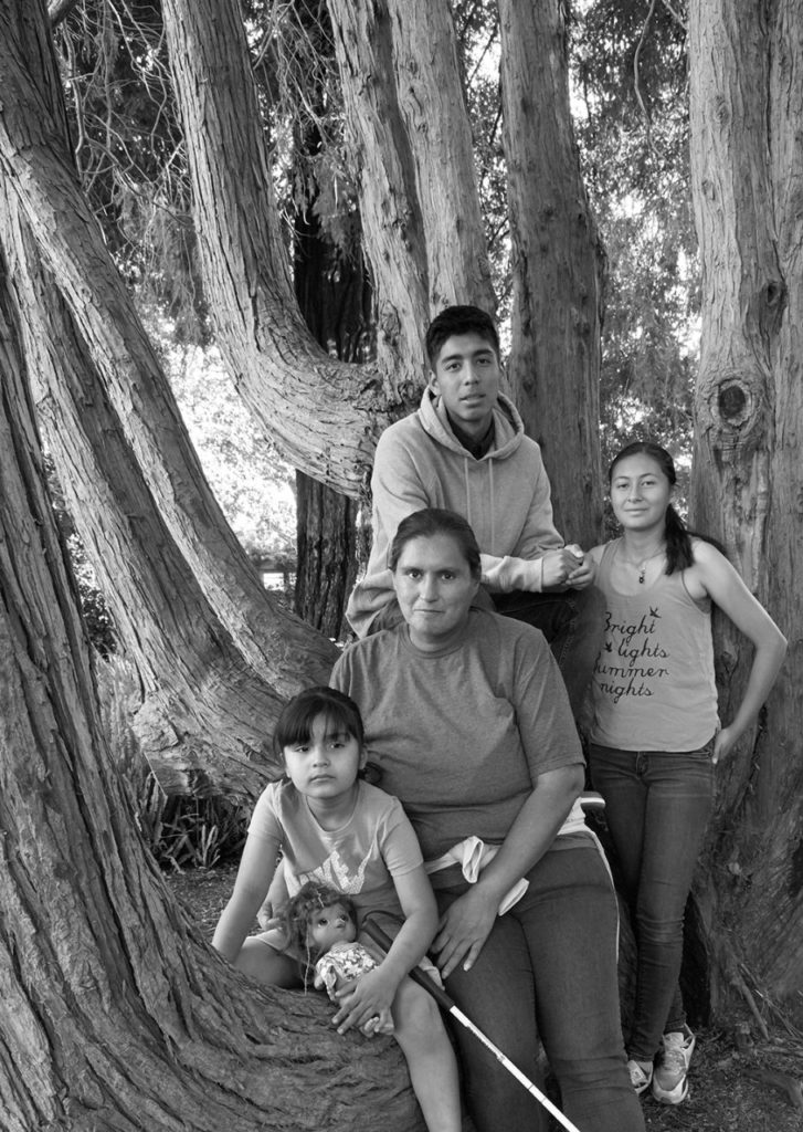 Mother with her two daughters and a son, standing by a tree