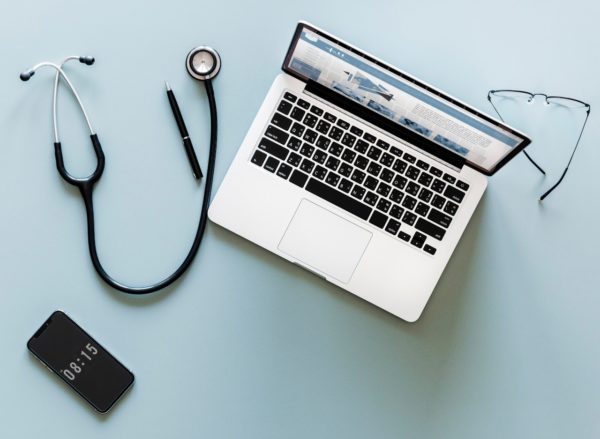 Computer, stethoscope, phone and eyeglasses. / Photo by rawpixel on Unsplash