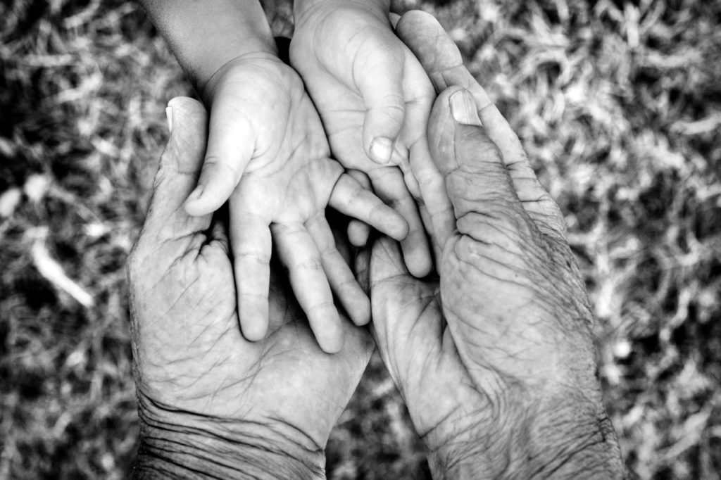 Older and younger person holding hands. Photo by ITummy