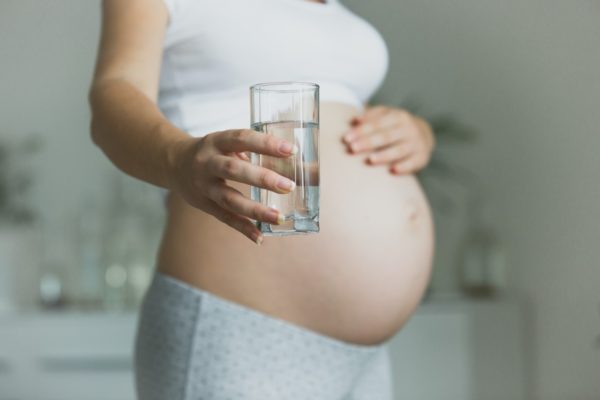 Photo of a pregnant woman holding a glass of water, by kryzhov/Shutterstock.com/ Shutterstock image