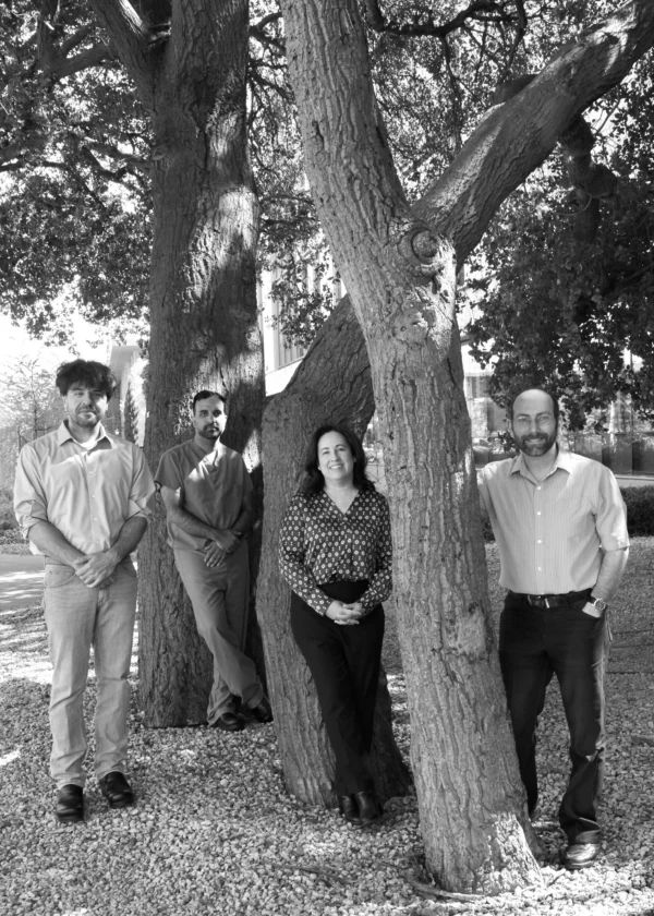 Black and white photo of four researchers standing near a tree on the Stanford University campus.