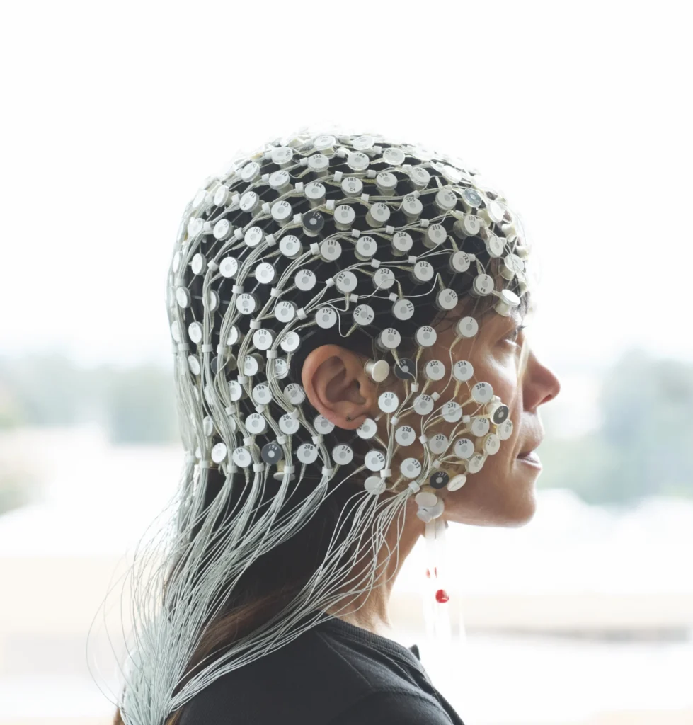 Photo of a women wearing a cap of a electrodes that capture brain data.