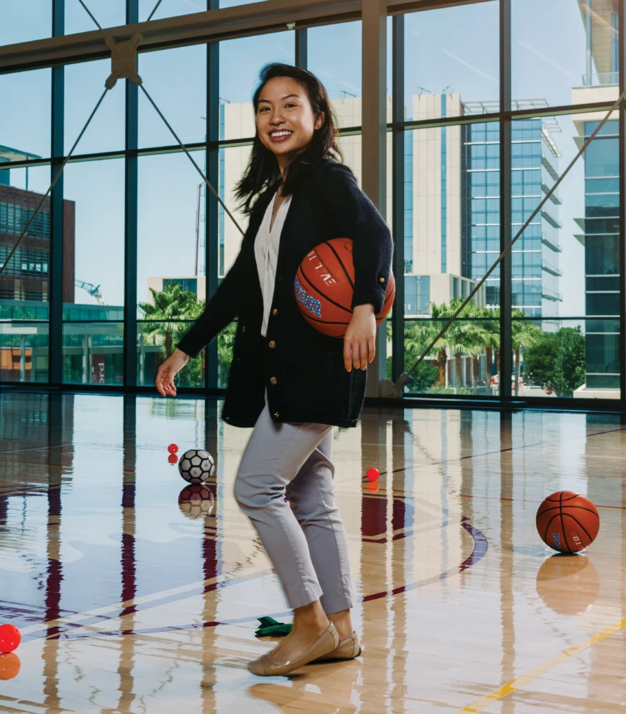 Image of Chantal Nguyen, MD, a clinical assistant professor of orthopaedic surgery, holding a basketball in an indoor court.